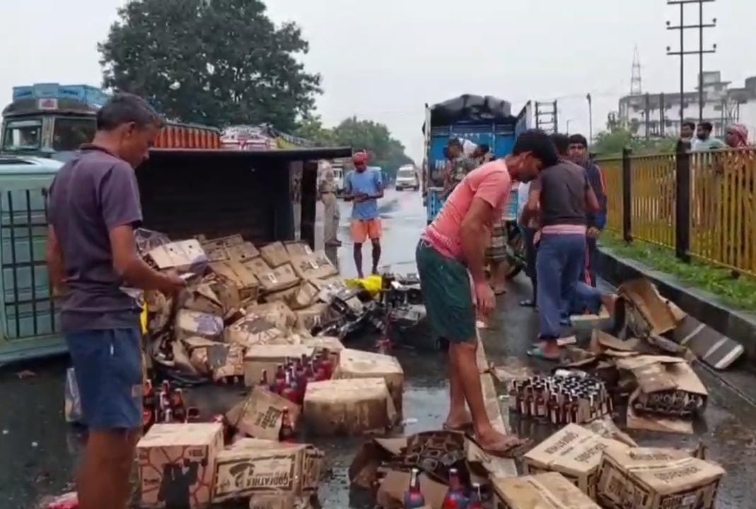 धनबादः बरवाअड्डा में शराब लदी मैजिक वैन पलटी, लाखों की शराब सड़क पर बिखरी